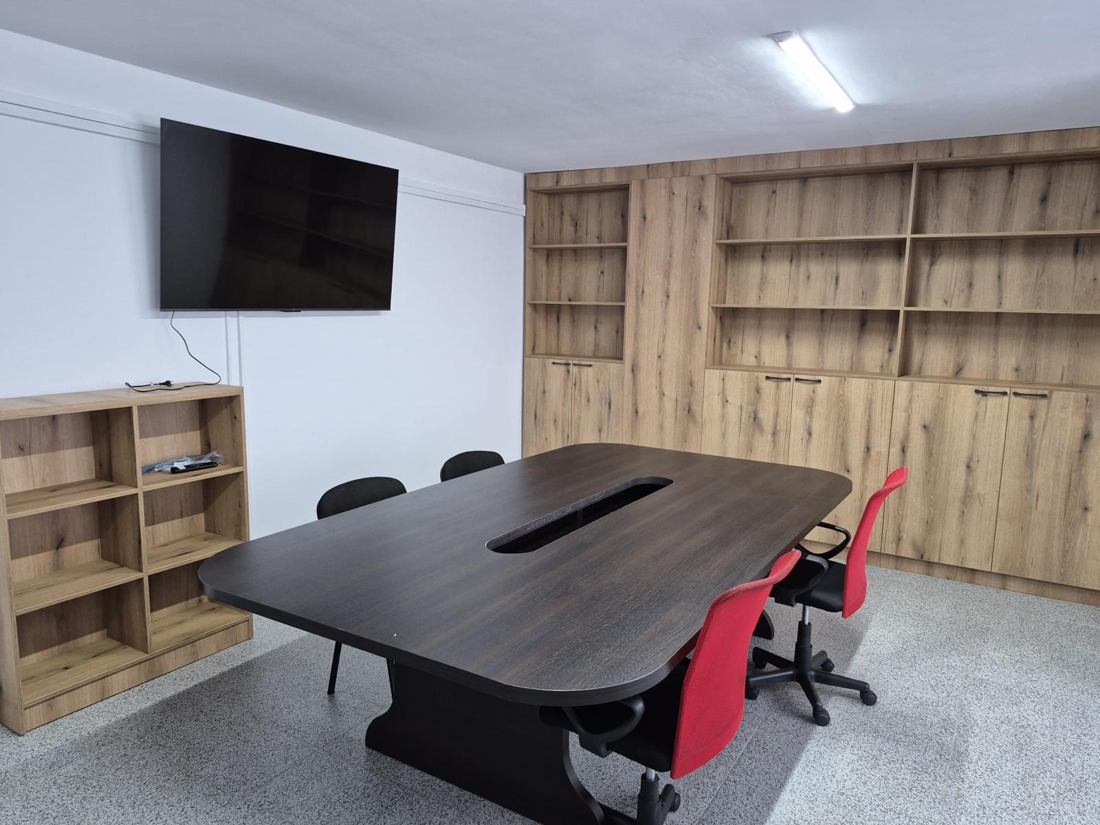 Sală de ședință cu masă centrală și mobilier de depozitare din lemn
