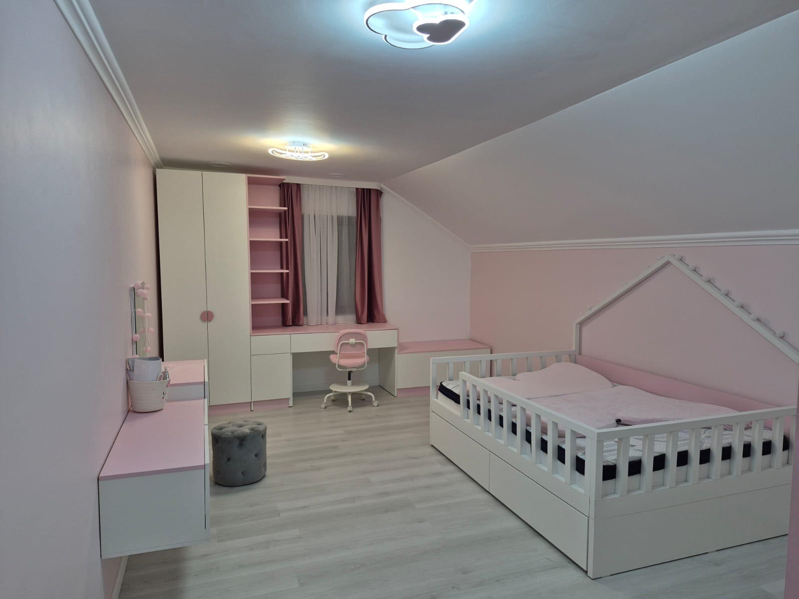 Cameră de copil roz și albă, cu pat, birou și mobilier integrat