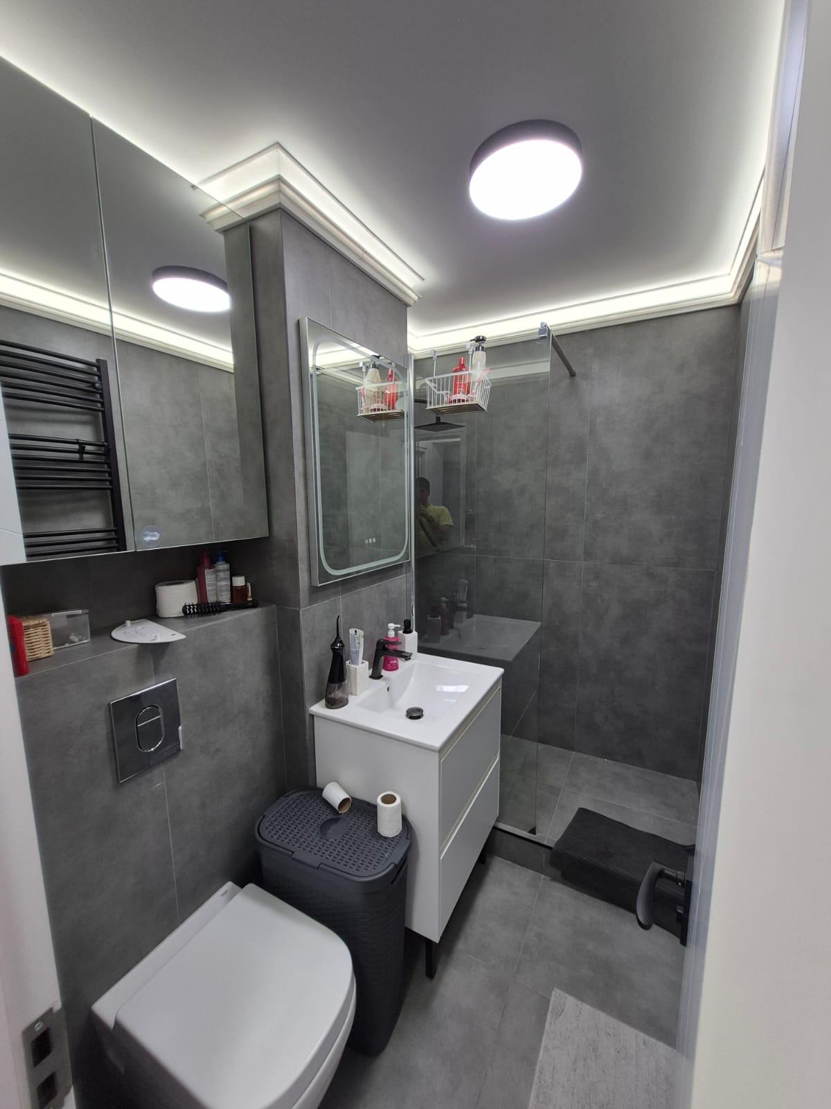 Baie după renovare, cu placări gri și duș walk-in
