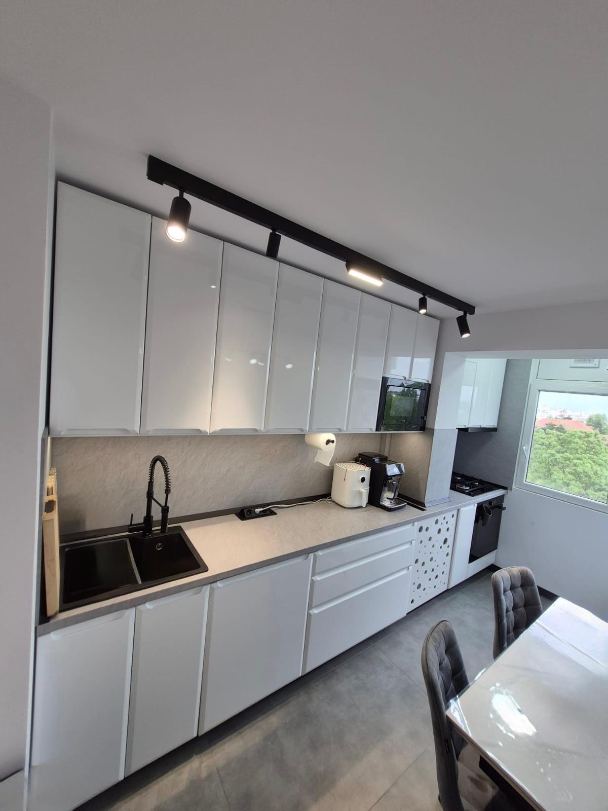 Bucătărie după renovare, cu mobilier alb și masă integrată