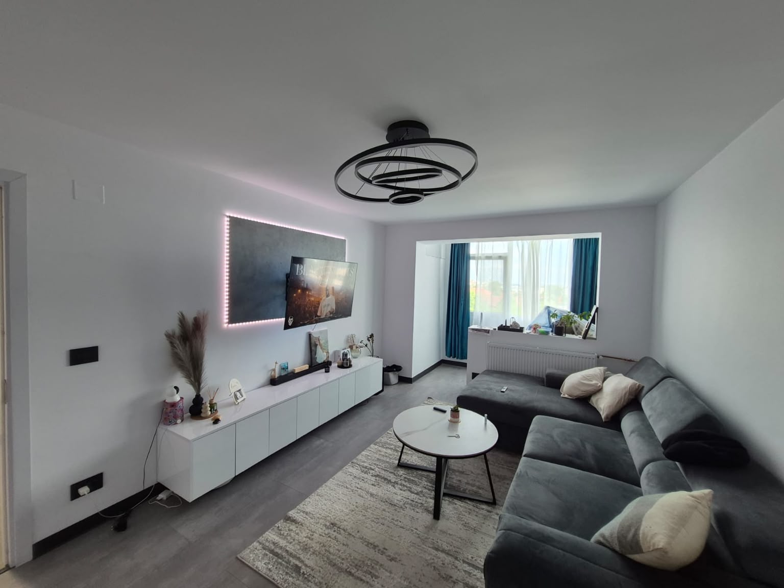 Living modern în tonuri de gri, cu mobilier alb și iluminat ambiental